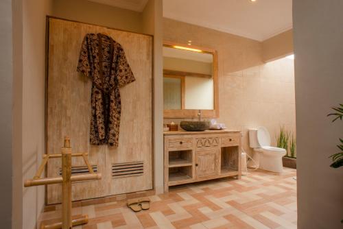 Auma Villa by Prasi في أوبود: حمام مع مرحاض وروب معلق على الباب