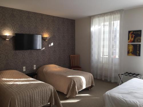 a hotel room with two beds and a flat screen tv at H&ocirc;tel Restaurant La Boule d'Or in Barbezieux