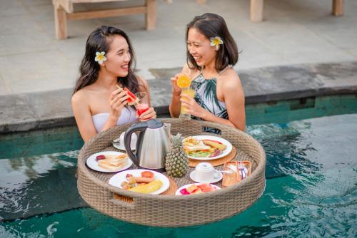 due donne sedute a un tavolo circolare in una piscina di Auma Villa by Prasi ad Ubud