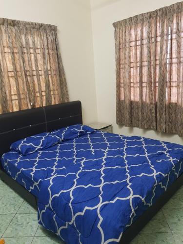 a bedroom with a blue bed and two windows at Homestay Che Wan in Kuantan