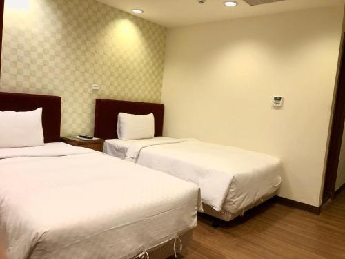 a hotel room with two beds with white sheets at Kousin Hotel in Kaohsiung