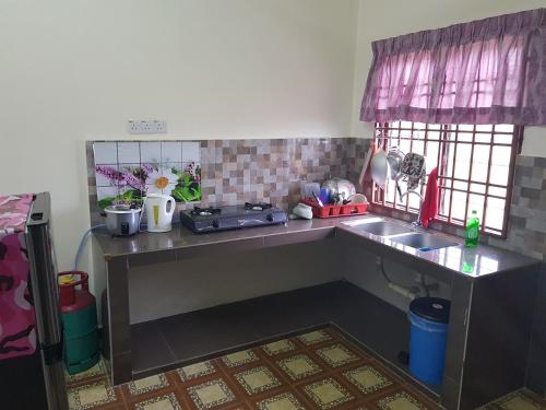 a kitchen with a counter and a sink and windows at Homestay Che Wan in Kuantan