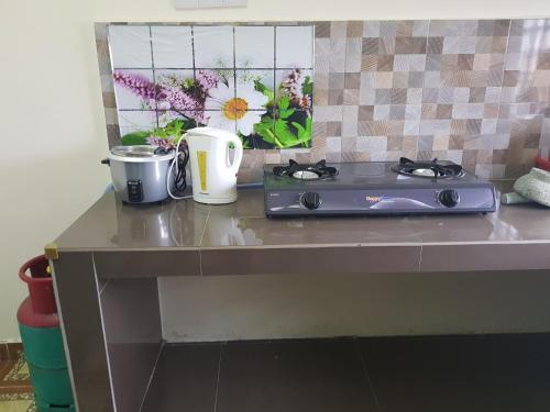 a counter top with a stove and flowers on it at Homestay Che Wan in Kuantan