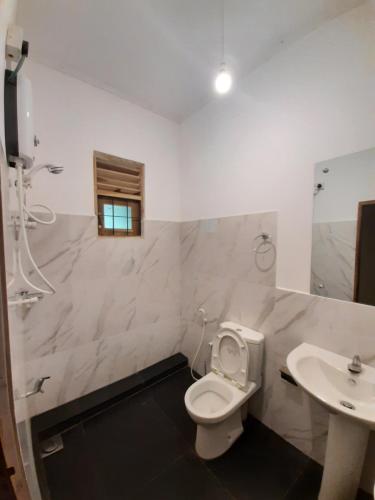 a bathroom with a toilet and a sink at Nature's Hideout Holiday Home in Mirigama