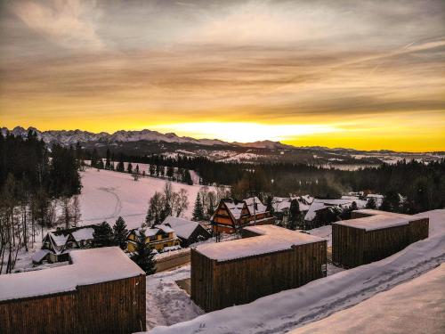 a village covered in snow with the sunset in the background at Rzepiska Hills in Rzepiska