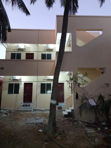 a building with a palm tree in front of it at Raghavi Tourist Home in Kanyakumari