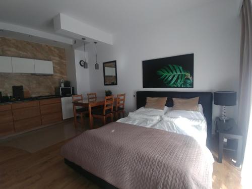 Sopot Holiday - Apartament przy plaży في سوبوت: غرفة نوم بسرير وطاولة وكراسي