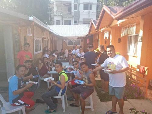 a group of people sitting at tables with plates of food at Mama Hostel & Guest House in El Nido
