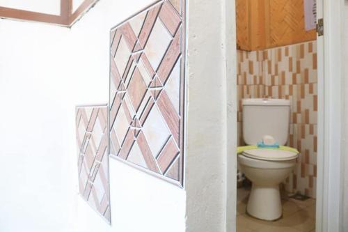 a bathroom with a toilet and a tile wall at Mama Hostel & Guest House in El Nido