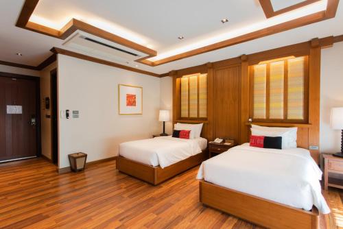 two beds in a room with wooden floors at Phra Singh Village in Chiang Mai