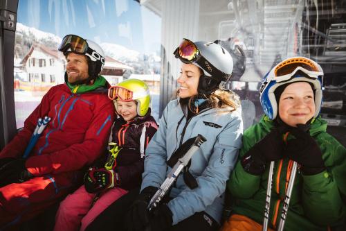 a group of people sitting on a ski lift at Vital Chalets in Schröcken