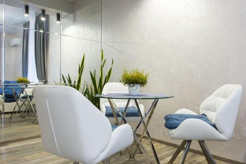 a dining room with white chairs and a table at New luxury Apartment in the Center on Konstitution Square in Kharkiv