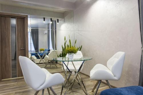 a dining room with a glass table and white chairs at New luxury Apartment in the Center on Konstitution Square in Kharkiv