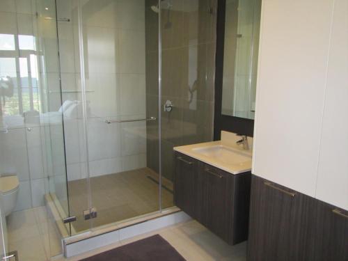 a bathroom with a glass shower and a sink at MENLYN MAINE - One Bedroom Penthouse - NO LOAD SHEDDING!! in Pretoria