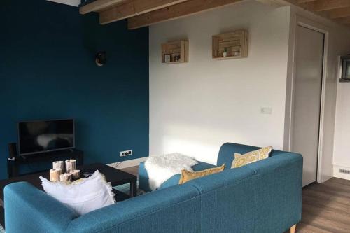 a living room with a blue couch and a tv at Ruim appartement in prachtige fiets-wandelomgeving in Abcoude