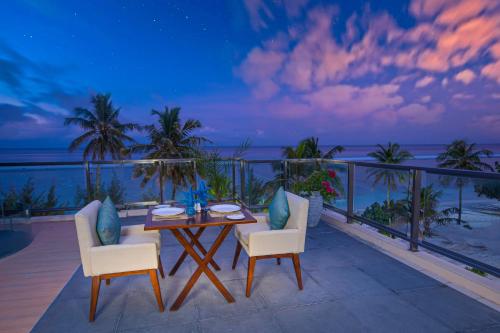 a table and chairs on a balcony with the ocean at Seasalter Maldives in Hulhumale