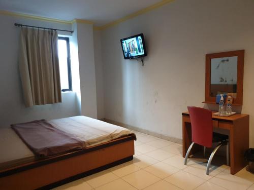 a bedroom with a bed and a desk and a television at SPOT ON 2831 Pondok Orange Family in Makassar