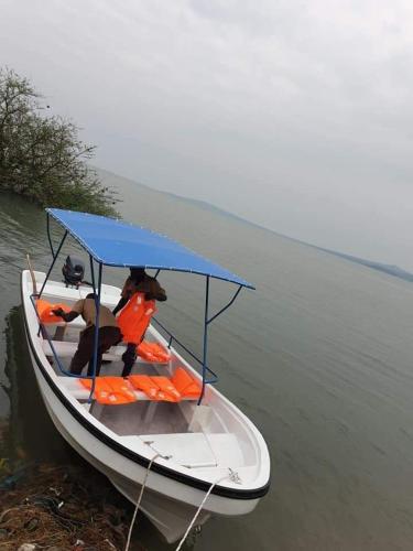 a boat with a blue roof on the water at VICTORIA SANDS LODGE in Mbita