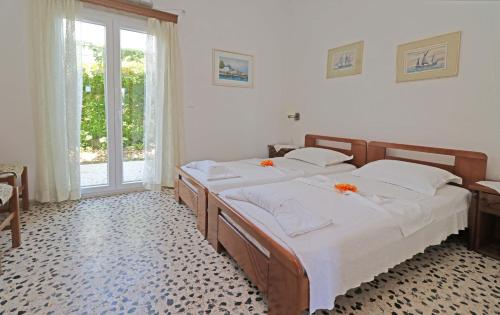 um quarto com 2 camas com lençóis brancos e uma janela em Angela Beach Apartments em Votsalákia