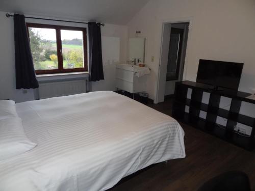 a bedroom with a large white bed and a window at Guesthouse Les Tilleuls in Fleurus