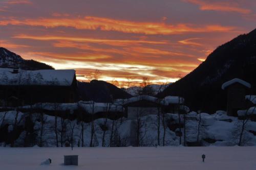 a sunset over a snow covered field with trees at Virgentaler Alp in Prägraten am Großvenediger