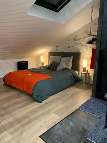 une chambre avec un grand lit avec une couverture orange dans l'établissement L'Atelier Planqué, au Mans