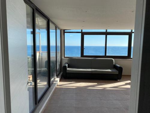 a couch in a room with a view of the ocean at Nick & Santo's Holiday Homes B&B in Giardini Naxos