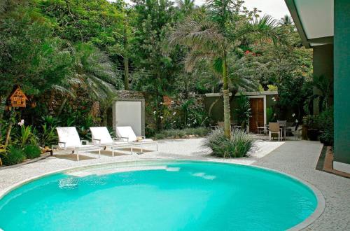 a swimming pool in a yard with chairs and trees at La Suite by Dussol in Rio de Janeiro