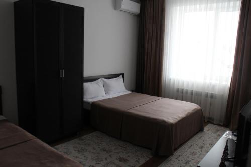 a small bedroom with a bed and a window at Апарт отель Welcome in Taldykorgan