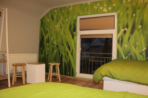 a bedroom with a green wall with a bed and a window at Label Semois Gite rural 3 épis in Bouillon