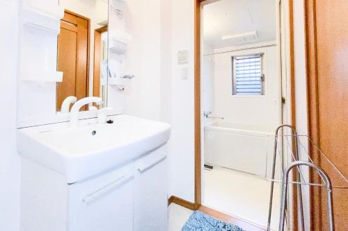 La salle de bains blanche est pourvue d'un lavabo et d'une baignoire. dans l'établissement Yahiro 4-chome House 1F, à Tokyo