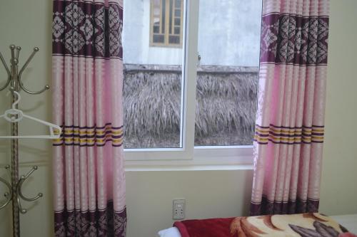 a bedroom with two curtains and a window at Phong Nha Homestay in Phong Nha