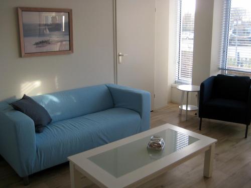 a living room with a blue couch and a coffee table at Vakantieappartementen Stuifkenszand in Hoek van Holland