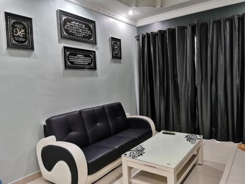 a living room with a black couch and a table at DF ZaheenulFitri Homestay (Muslim Homestay) in Seremban