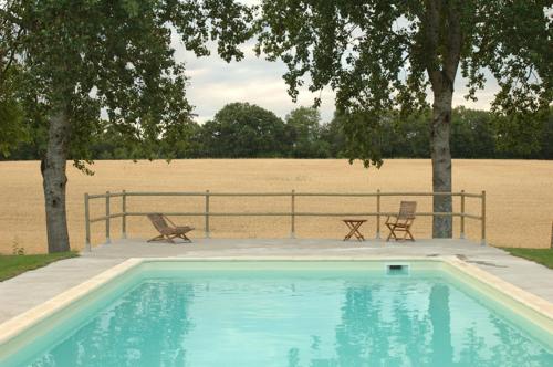 a swimming pool with two chairs next to a field at Bed and Breakfast - Château du Vau in Ballan-Miré