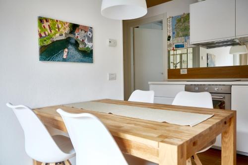 a kitchen with a wooden table and white chairs at Appartamenti 1 in Dervio