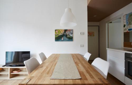 a dining room with a wooden table and white chairs at Appartamenti 1 in Dervio