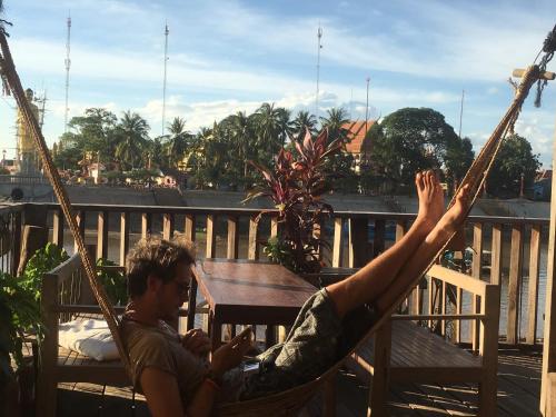 a man laying in a hammock on a balcony at ST 63 Home Stay & Tour Kampong Khleang in Kâmpóng Khleăng