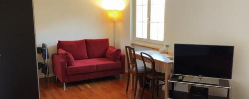 a living room with a red chair and a desk at B&B Tomsi in Pratteln