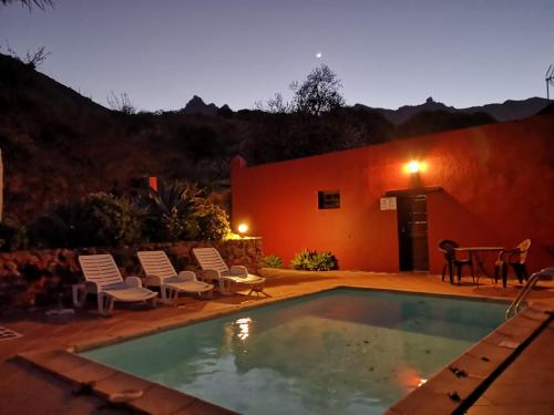 a swimming pool with chairs and a house at FINCA EL PEDREGAL in Valsequillo