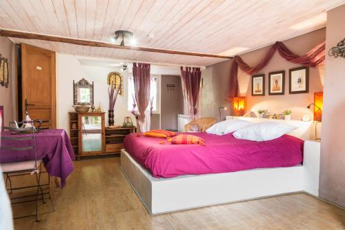 ein Schlafzimmer mit einem großen Bett mit rosa Bettwäsche und Kissen in der Unterkunft Maison d'hôtes L'îlot bambou in Avignon