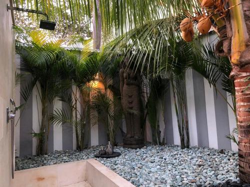a garden with palm trees and a statue at Hari Indah Boutique Hotel & Spa in Uluwatu