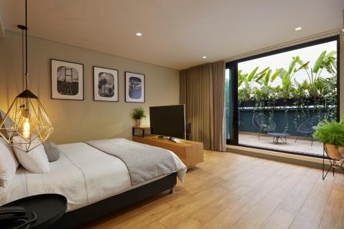 メデジンにある14 Urban Hotelのベッドとテレビとバルコニーのある寝室