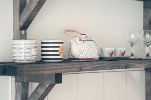a shelf with cups and a tea pot on it at Triantafilia Guesthouse in Áyioi Apóstoloi