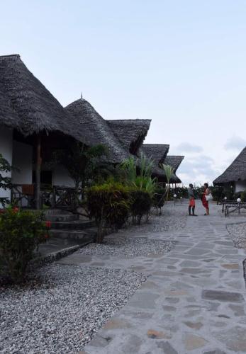a row of houses with thatched roofs and a pathway at BeB Sardegna2 Anjumasa village in Watamu