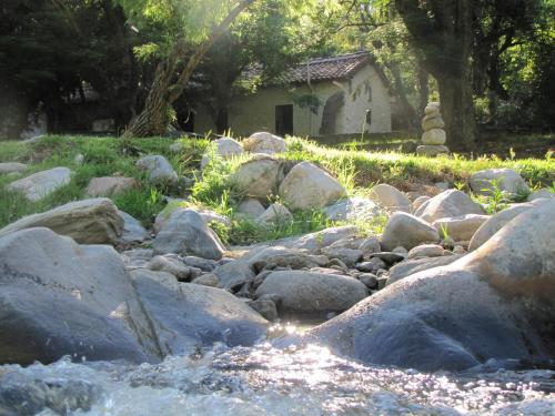 un río con rocas y una casa en el fondo en La Casona del Río en Valle Hermoso
