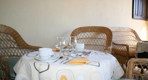 a table with a white table cloth with cups and wine glasses at Posada La Colodra in Los Tojos