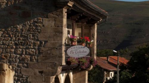 a sign on the side of a building with flowers at Posada La Colodra in Los Tojos