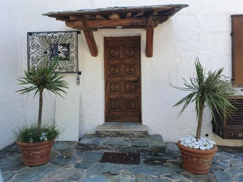 a house with a wooden door and two potted plants at maison de charme avec piscine et vue exceptionnelle in Scolca