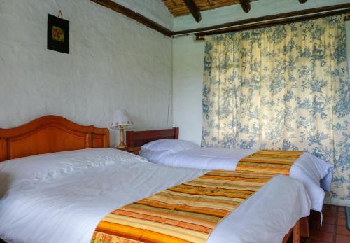 two twin beds in a bedroom with curtains at Hostería Colibri Aeropuerto in Tababela
